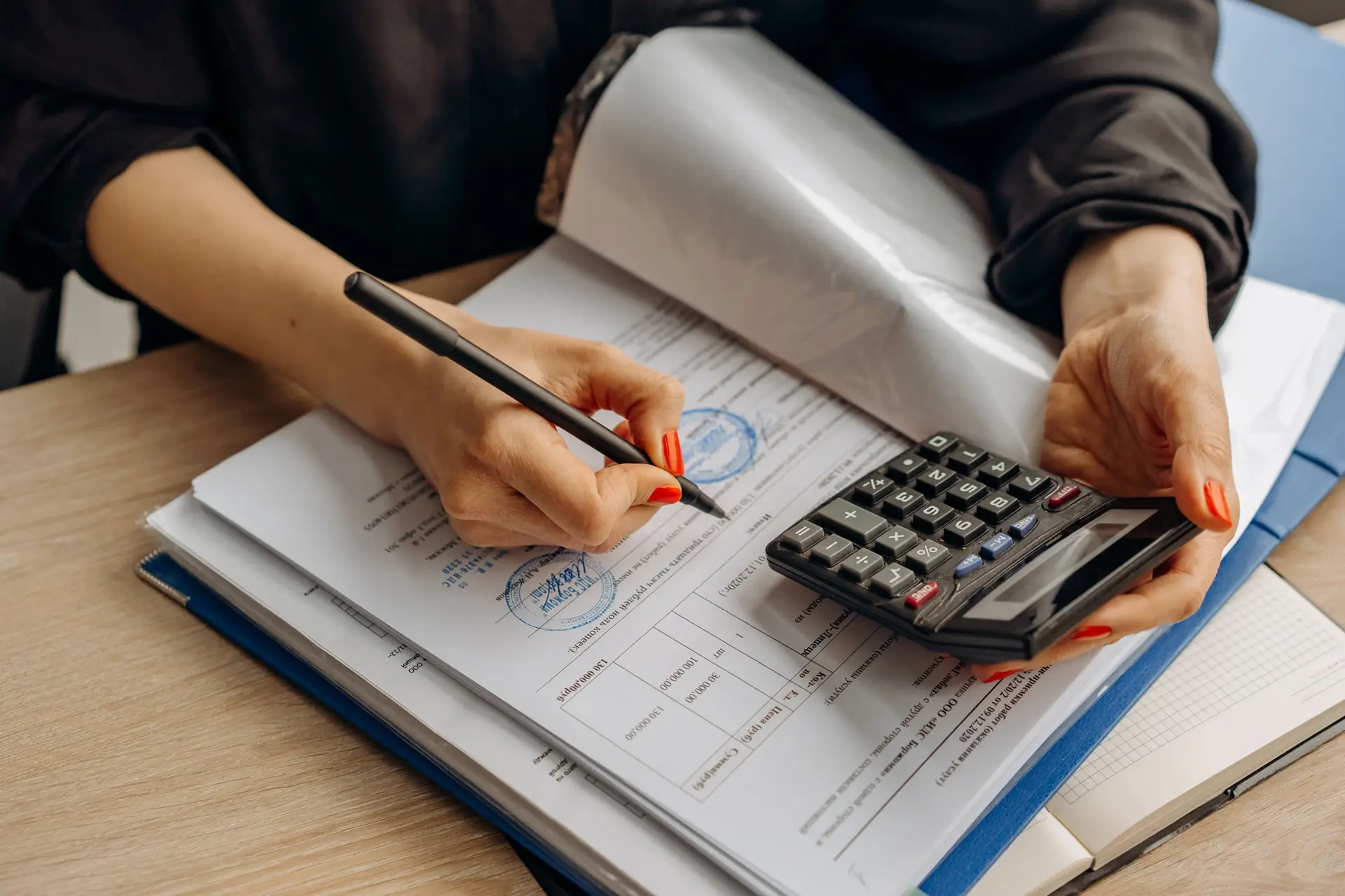Persona revisando un documento contable con una calculadora